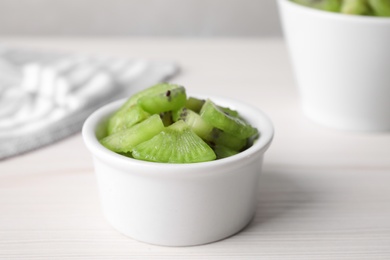 Photo of Bowl with kiwi slices on white table