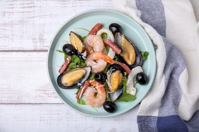 Plate of delicious salad with seafood on white wooden table, flat lay