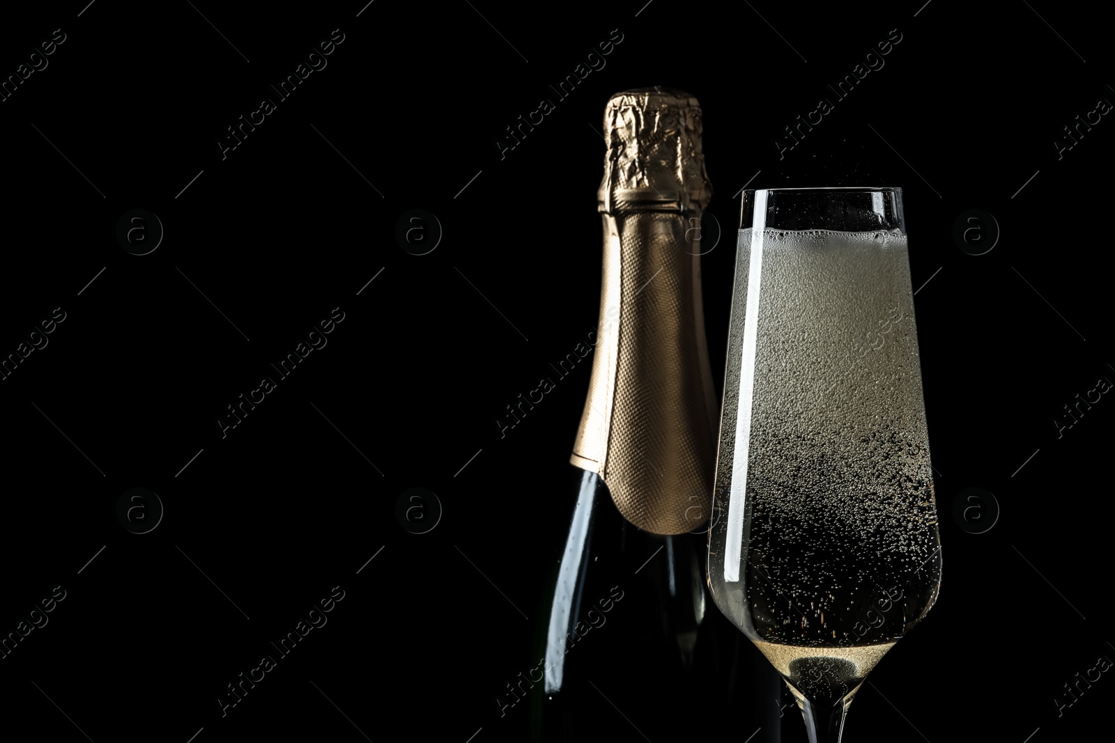 Photo of Bottle and glass of champagne on black background, space for text
