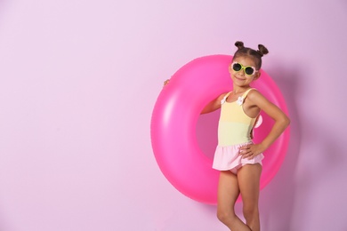 Cute little girl with inflatable ring on color background