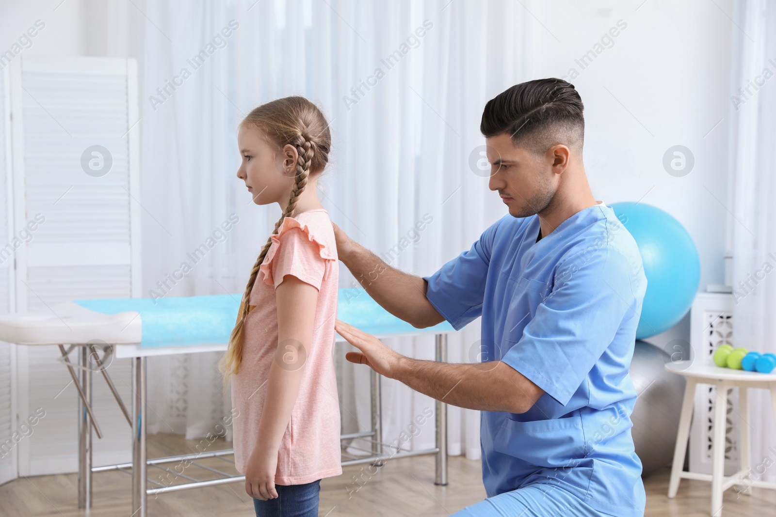 Photo of Orthopedist examining child's back in clinic. Scoliosis treatment