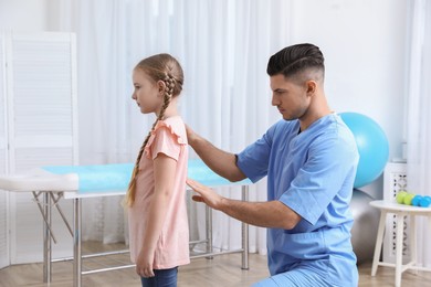 Photo of Orthopedist examining child's back in clinic. Scoliosis treatment