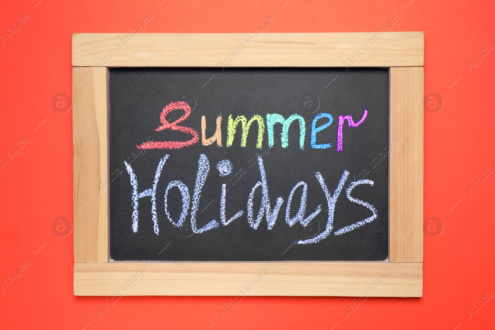 Photo of Chalkboard with phrase SUMMER HOLIDAYS on coral background, top view. School's out