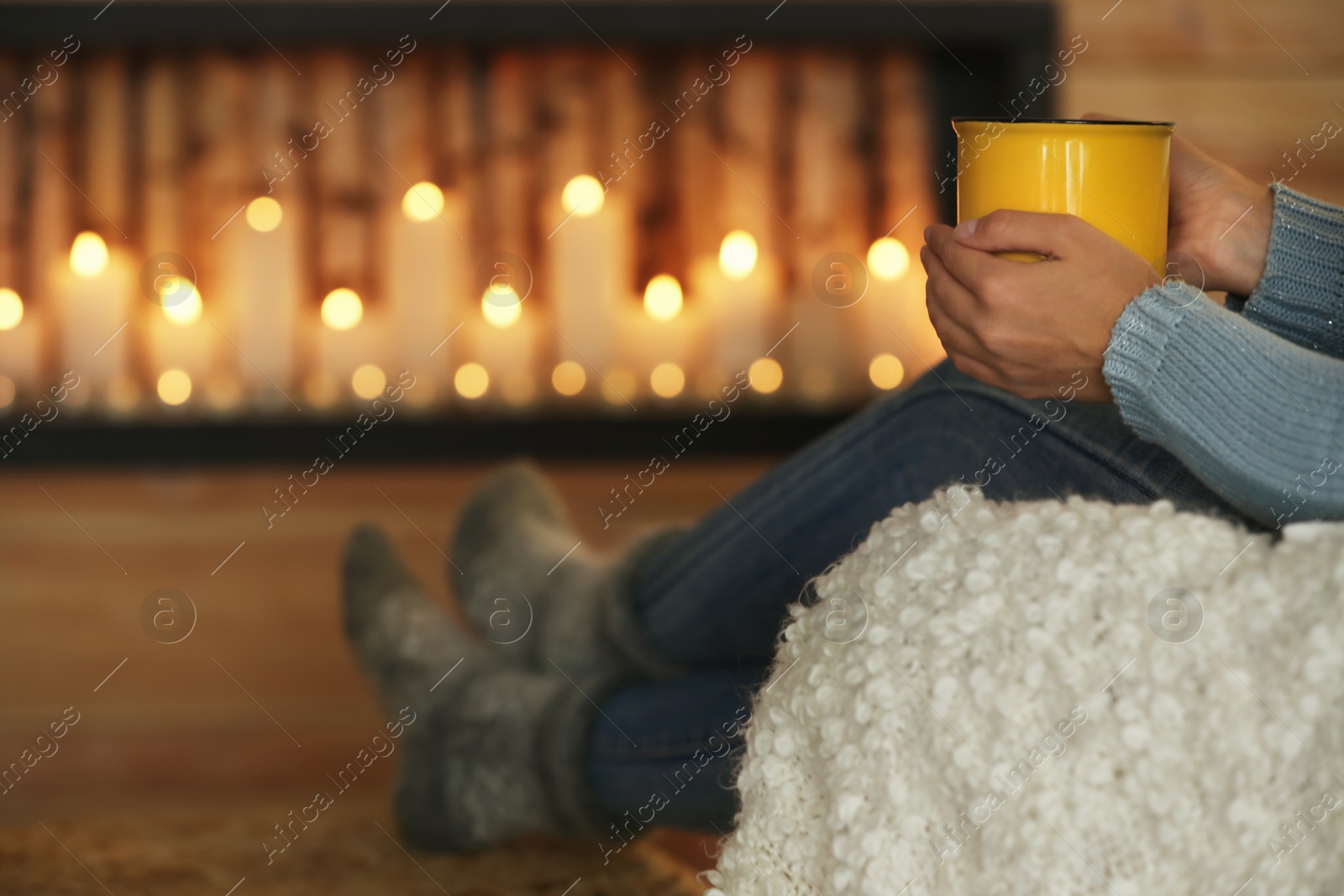 Photo of Woman with cup of hot drink near decorative fireplace indoors, closeup. Winter atmosphere