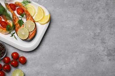 Photo of Tasty grilled salmon steaks and ingredients on light grey table, flat lay. Space for text