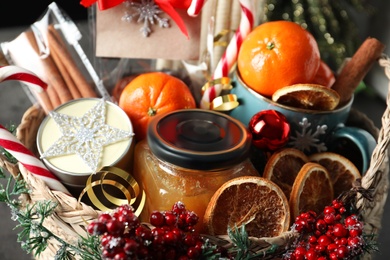 Wicker basket with gift set and Christmas decor on table, closeup