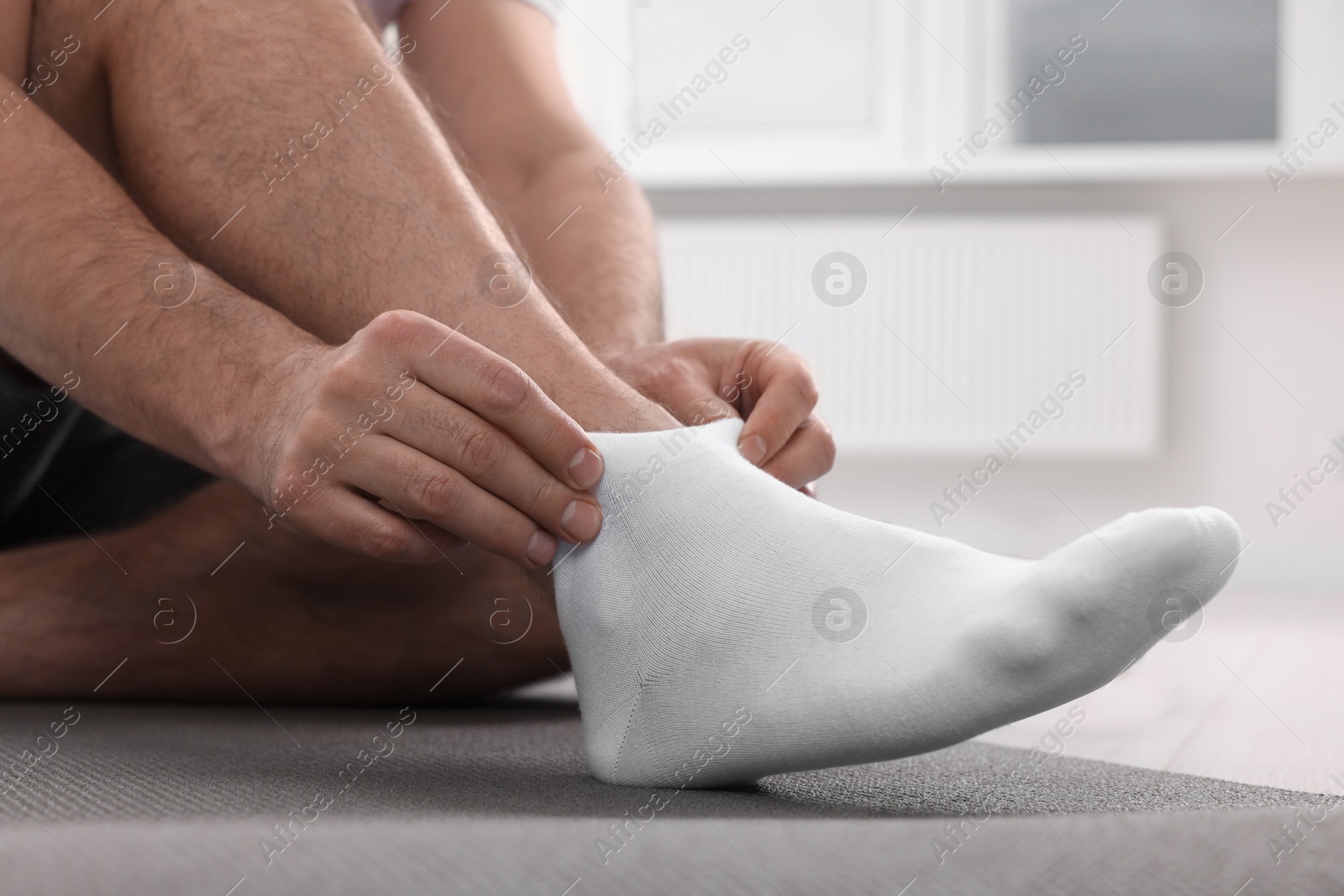 Photo of Man putting on white socks indoors, closeup