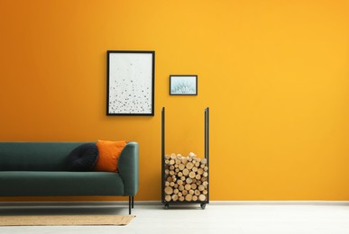 Photo of Stylish living room interior with sofa and firewood near orange wall