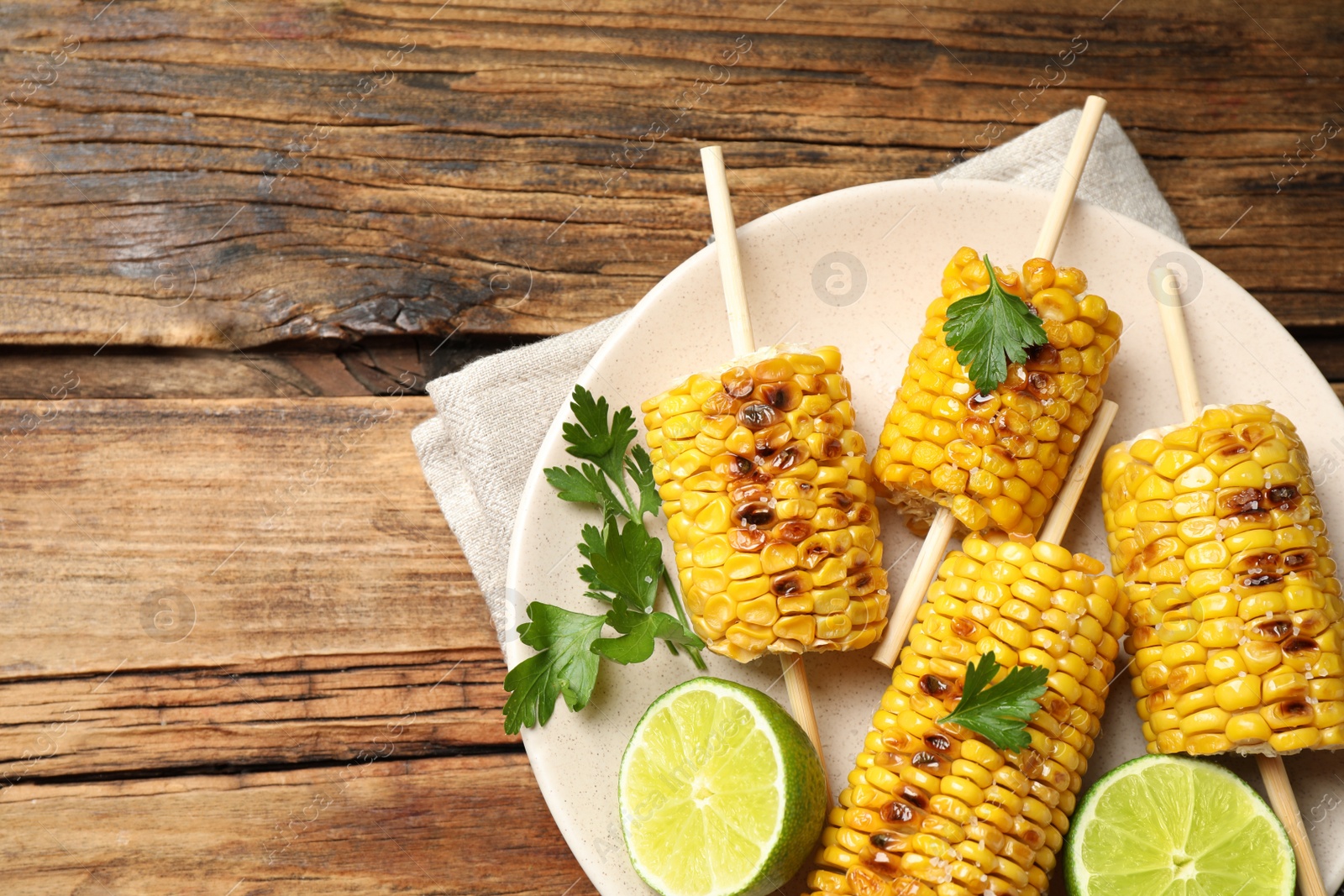 Photo of Tasty grilled corn on wooden table, top view. Space for text