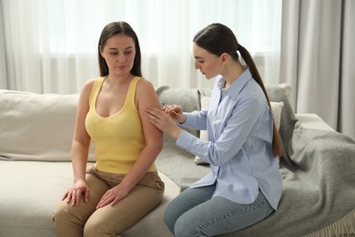 Woman giving insulin injection to her diabetic friend at home