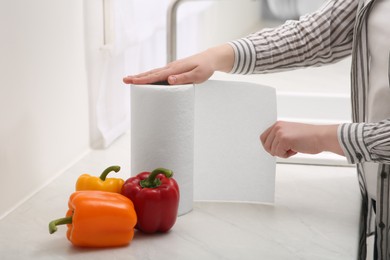 Photo of Woman tearing paper towels in kitchen, closeup