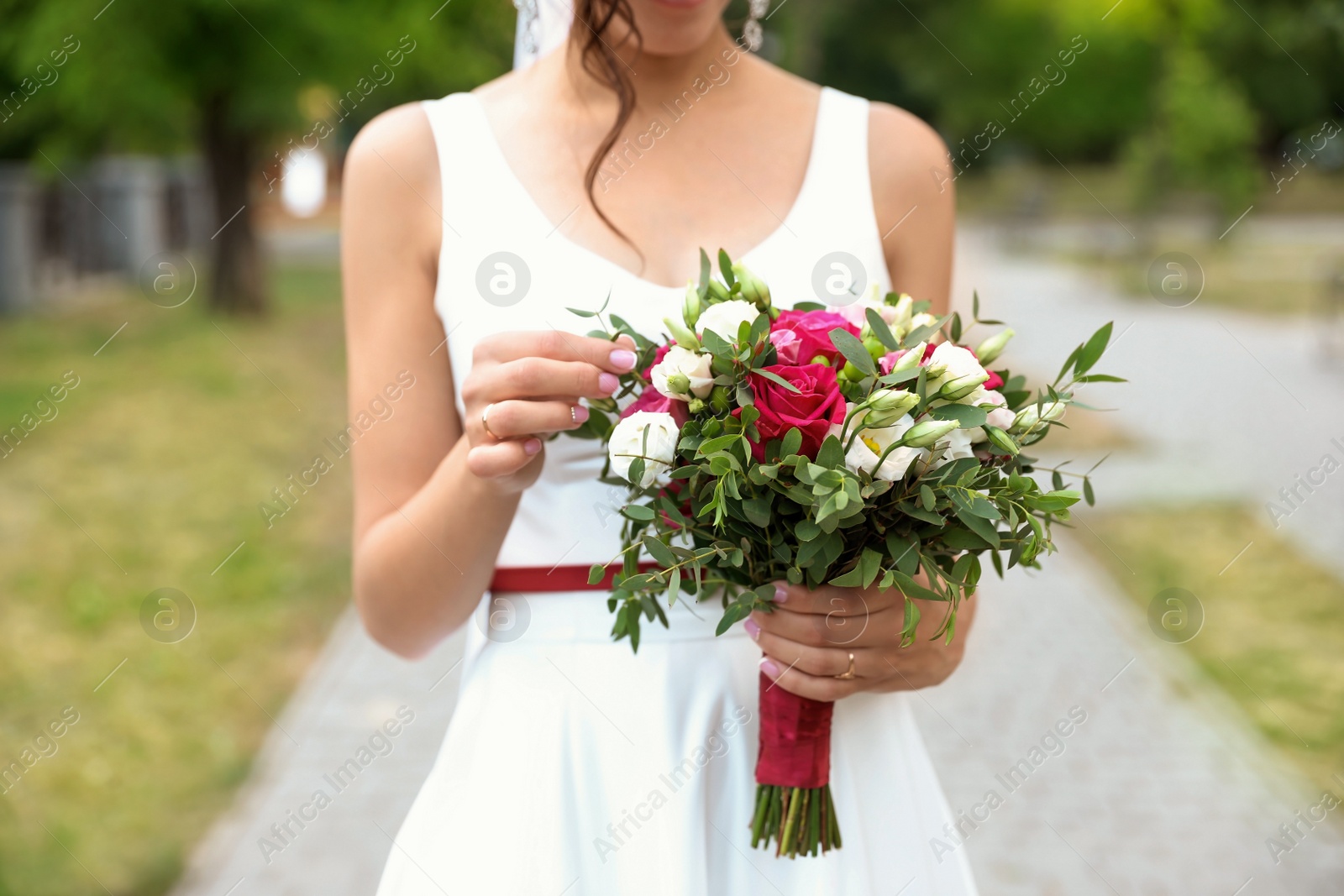 Photo of Woman in wedding gown with beautiful bridal bouquet outdoors, closeup