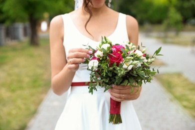 Photo of Woman in wedding gown with beautiful bridal bouquet outdoors, closeup