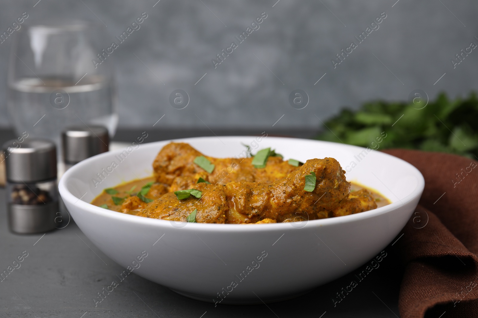 Photo of Delicious chicken with curry sauce on grey wooden table, closeup