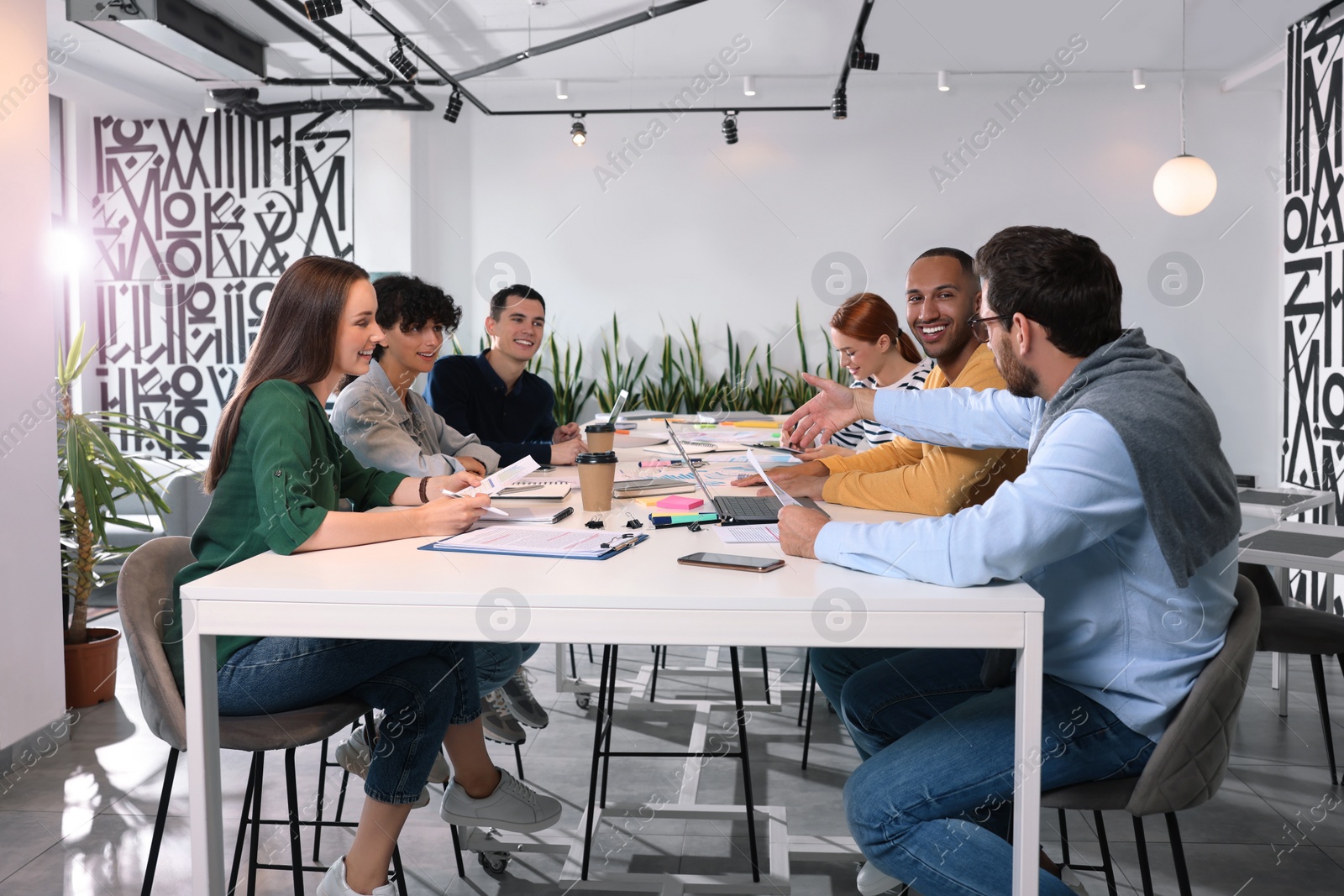 Photo of Team of employees working together at table in office. Startup project