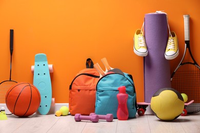 Many different sports equipment near orange wall indoors