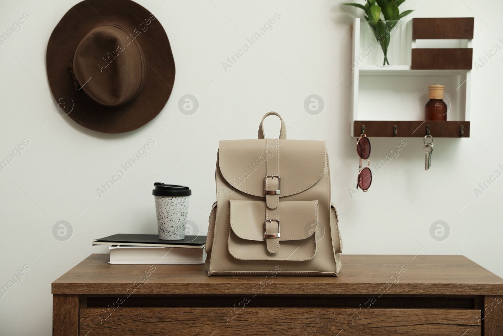 Photo of Stylish urban backpack on wooden chest of drawers in hallway