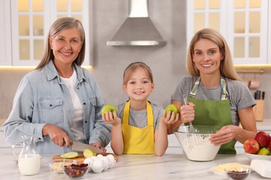 Photo of Three generations. Happy grandmother, her daughter and granddaughter cooking together in kitchen