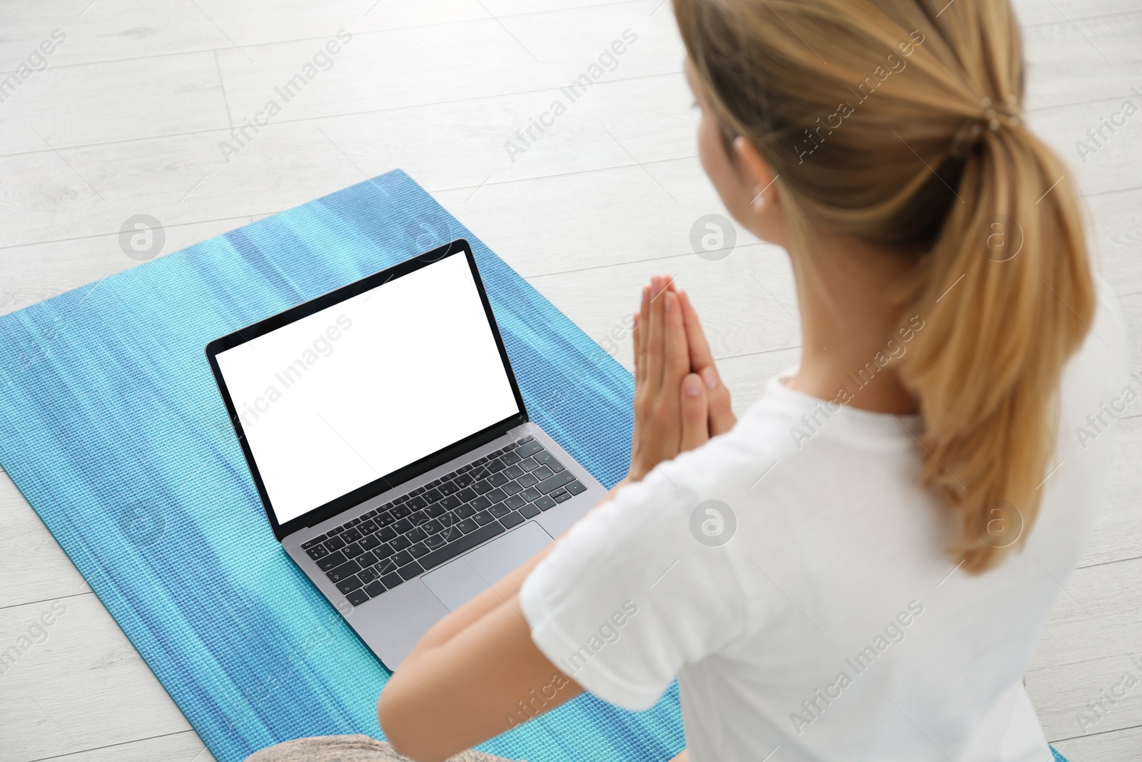 Photo of Woman having online video class via laptop at home. Distance yoga course during coronavirus pandemic