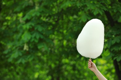 Photo of Woman holding sweet cotton candy outdoors, closeup. Space for text