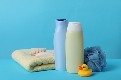 Photo of Baby cosmetic products, bath duck, accessories and towel on light blue background