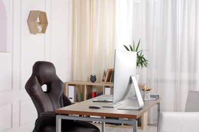 Photo of Director's workplace with wooden table, computer and comfortable armchairs. Interior design