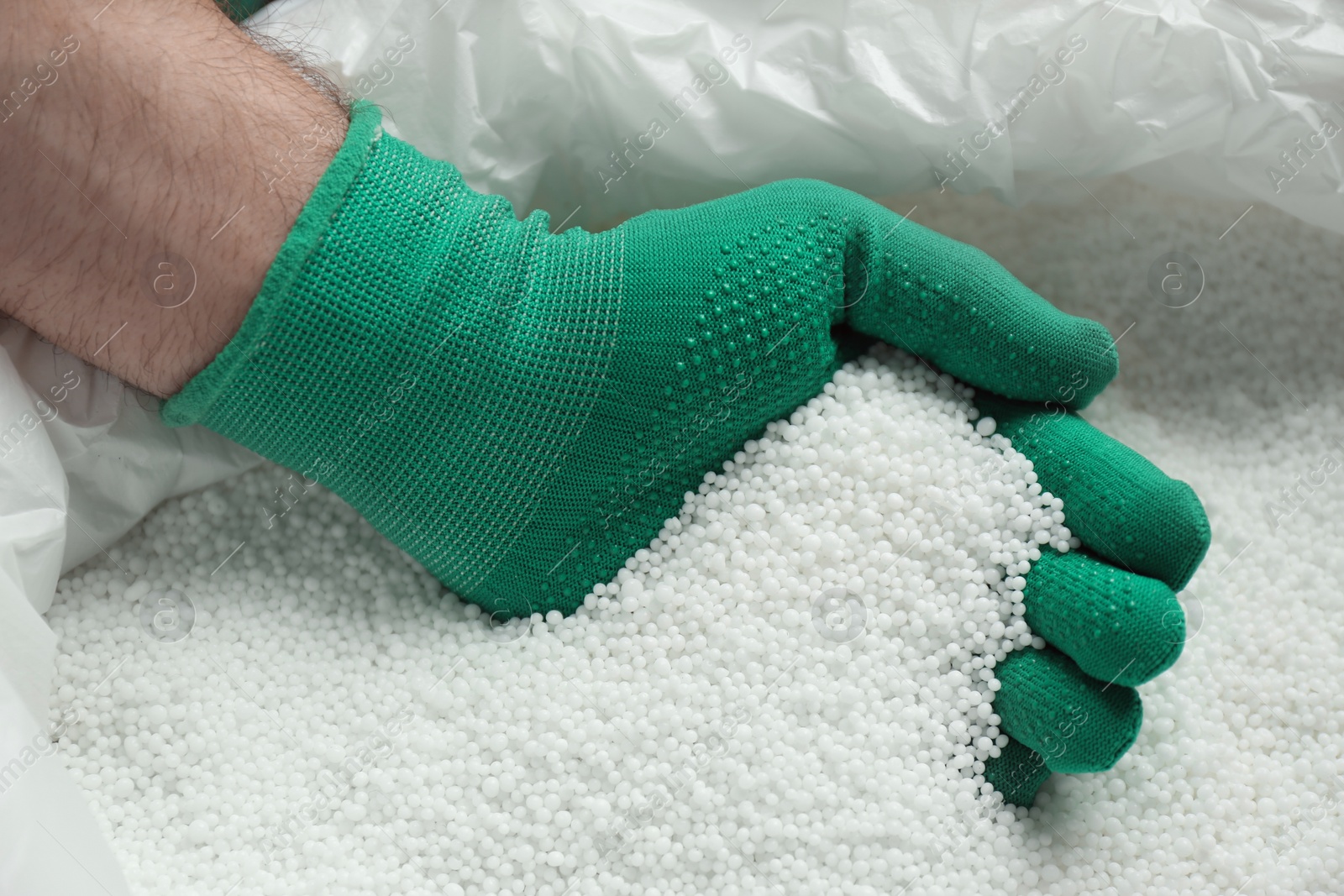 Photo of Farmer taking pellets of ammonium nitrate from bag, closeup. Mineral fertilizer