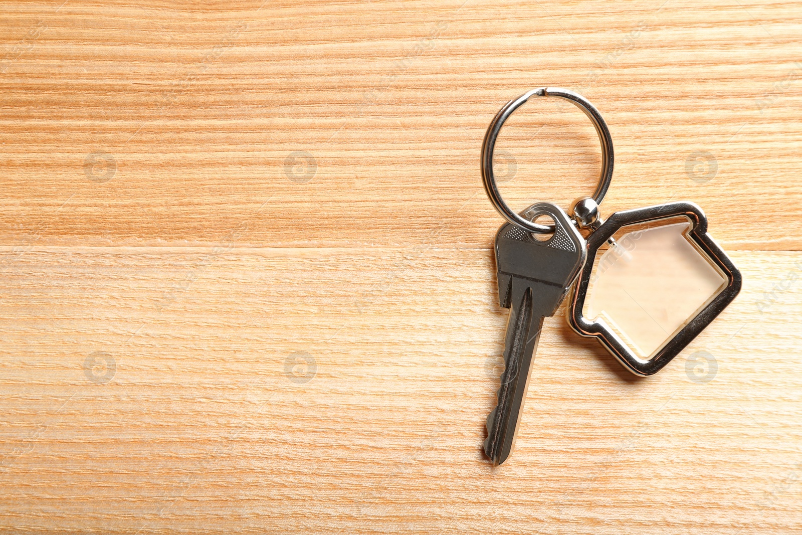 Photo of Key with trinket in shape of house on wooden background. Real estate agent services