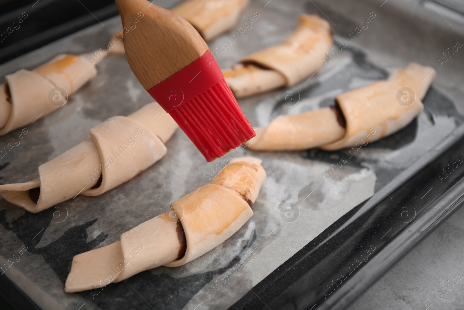 Photo of Spreading egg yolk on croissants, closeup