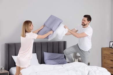 Photo of Couple having pillow fight while changing bed linens at home