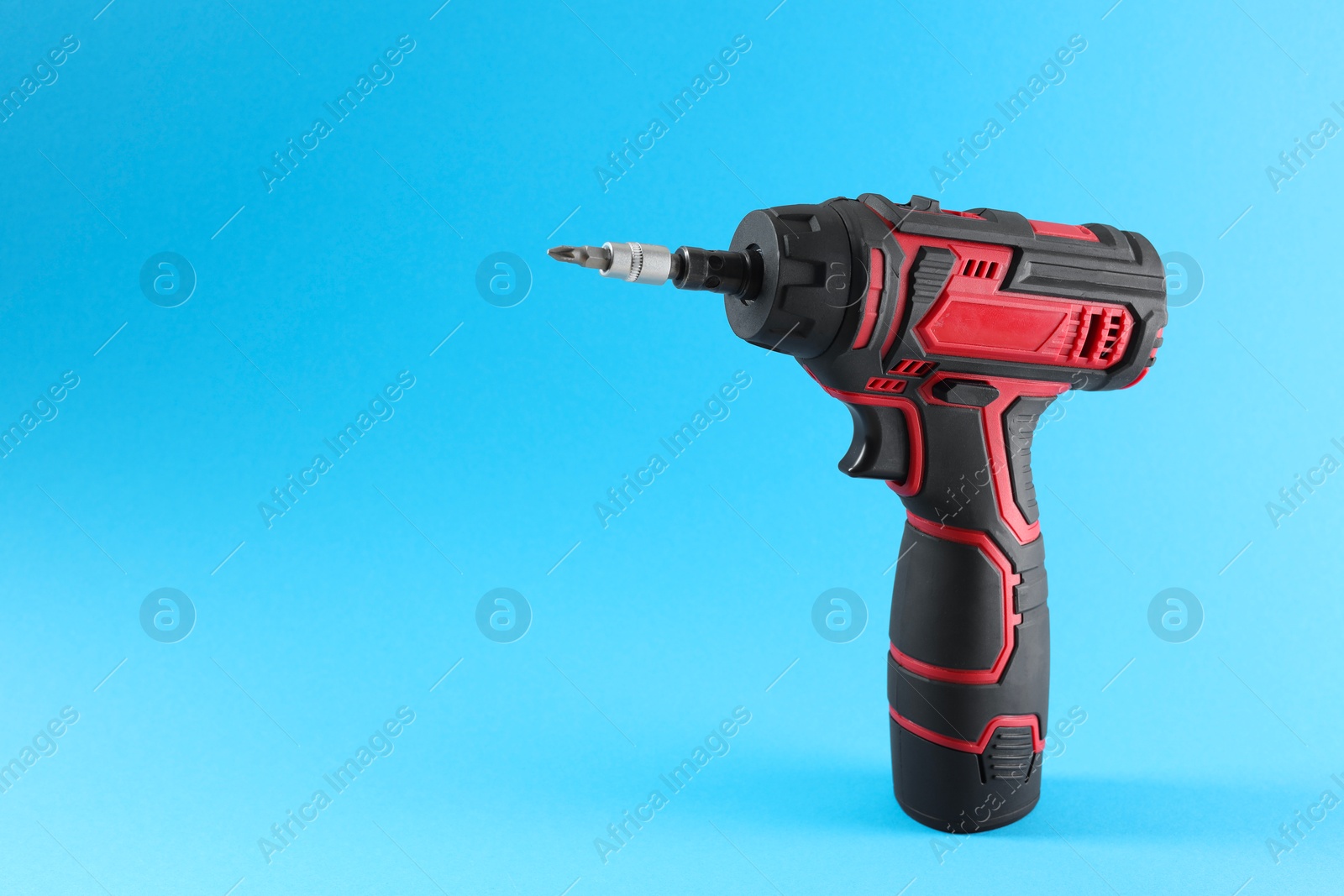 Photo of Modern electric screwdriver on light blue background. Space for text