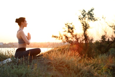 Photo of Young woman practicing yoga outdoors on sunset. Zen meditation