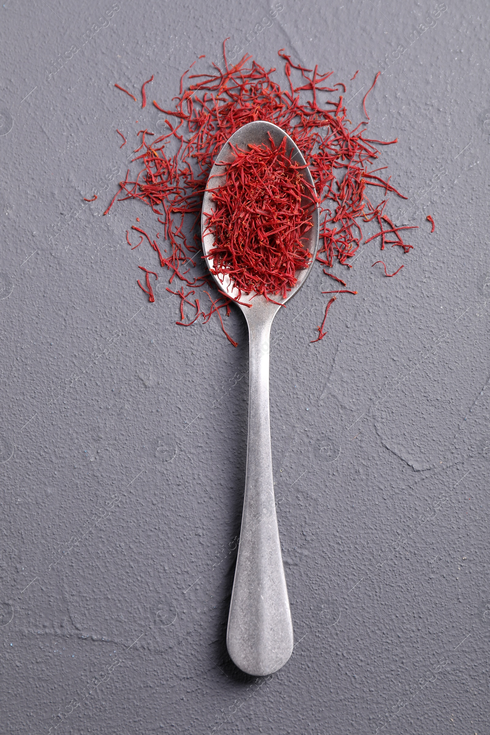 Photo of Aromatic saffron and spoon on gray table, top view