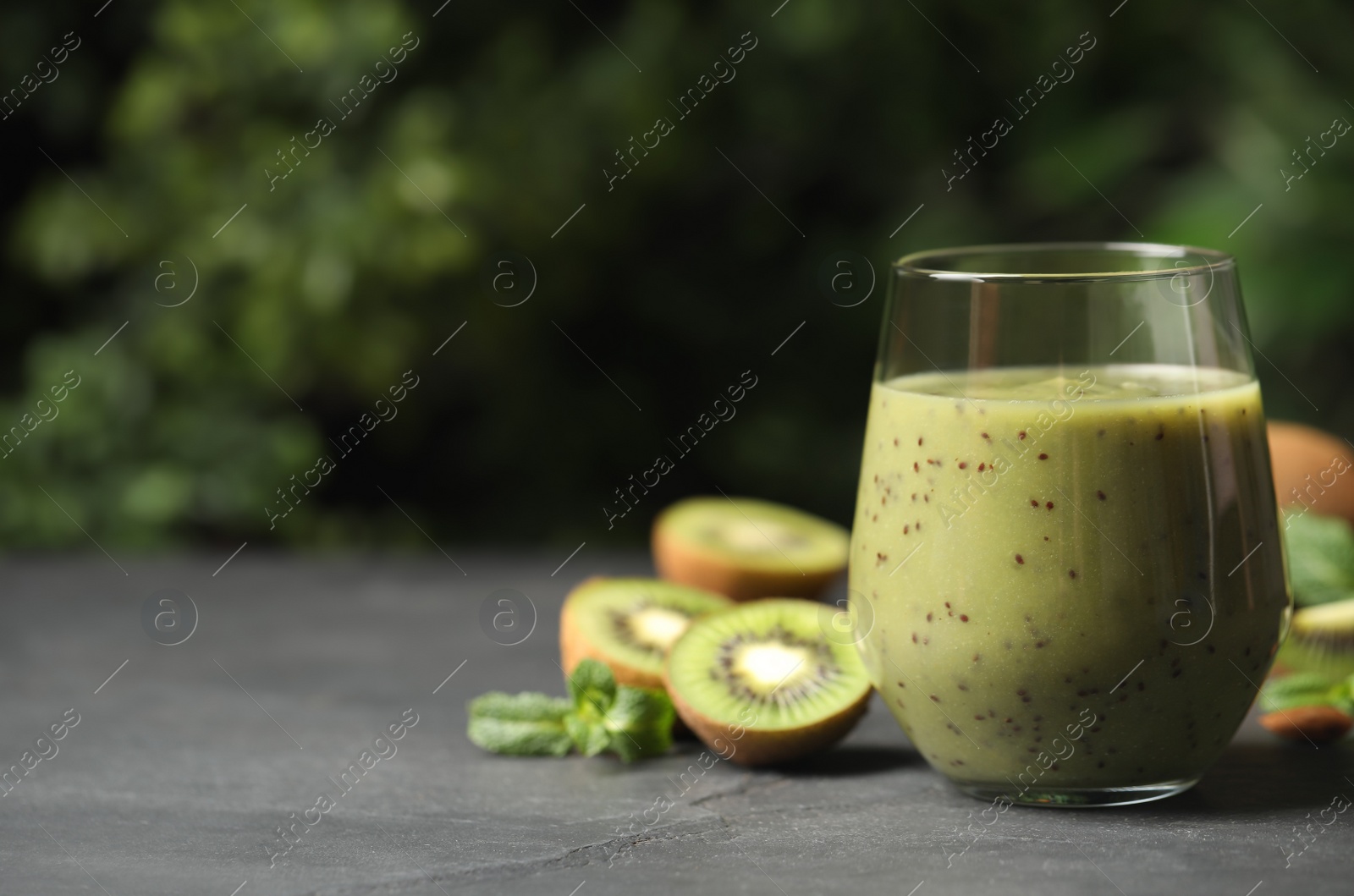 Photo of Delicious kiwi smoothie and fresh fruits on grey table. Space for text