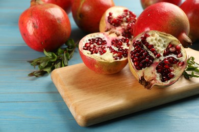 Photo of Ripe pomegranates on light blue wooden table