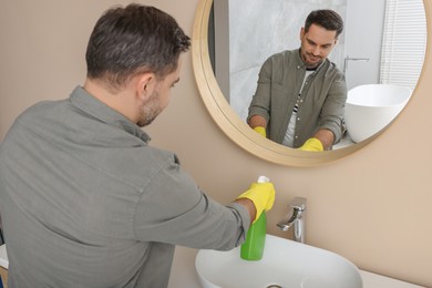 Photo of Man in rubber gloves with sprayer in bathroom