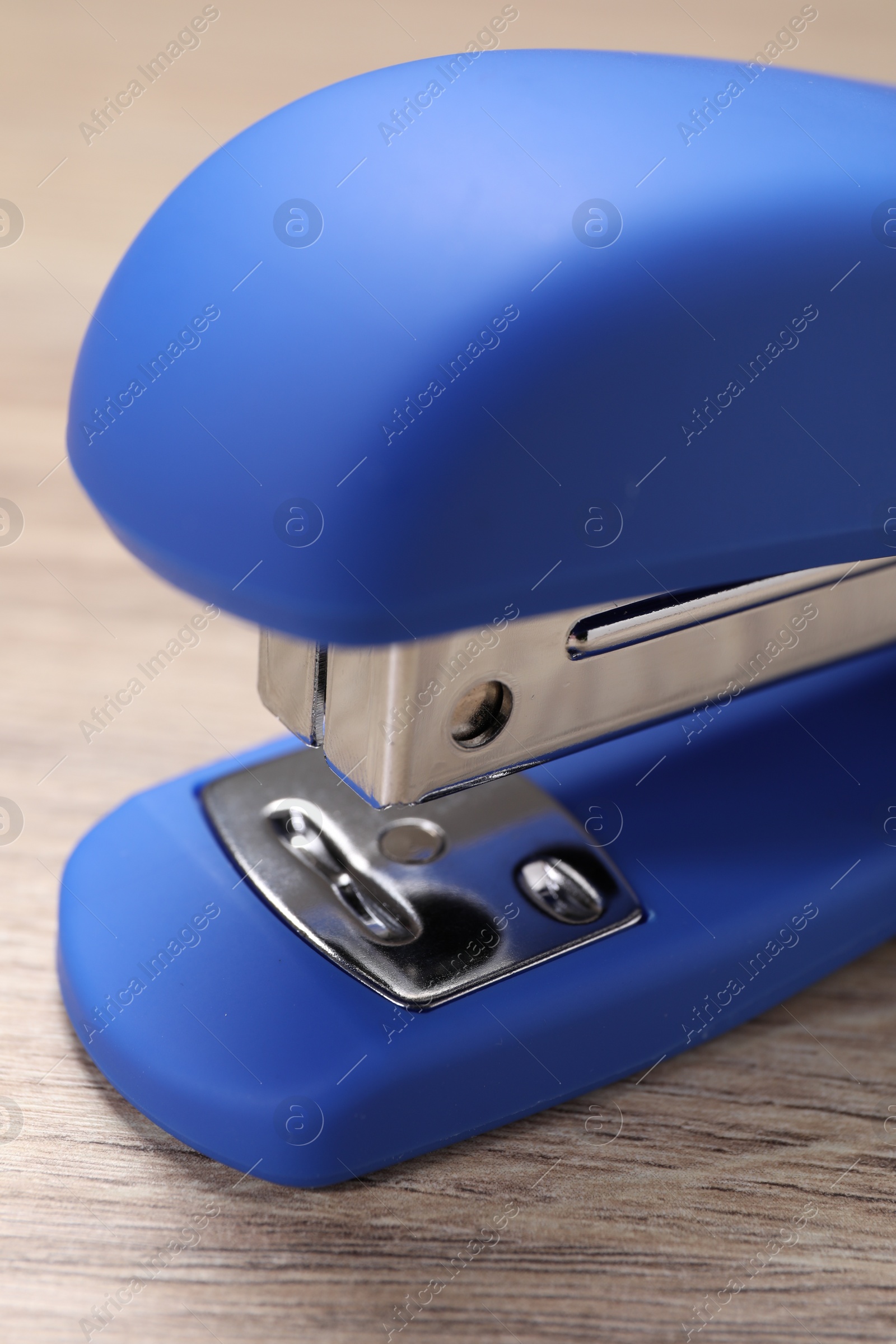 Photo of One blue stapler on wooden table, closeup