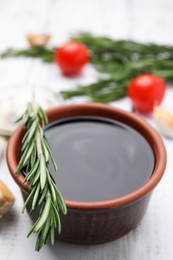 Photo of Organic balsamic vinegar and cooking ingredients on white wooden table, closeup