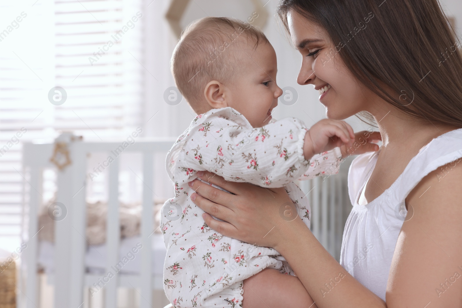 Photo of Happy young mother with her baby daughter in nursery. Space for text