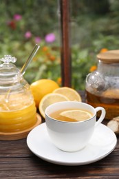 Photo of Cup of delicious tea with lemon and honey on wooden table