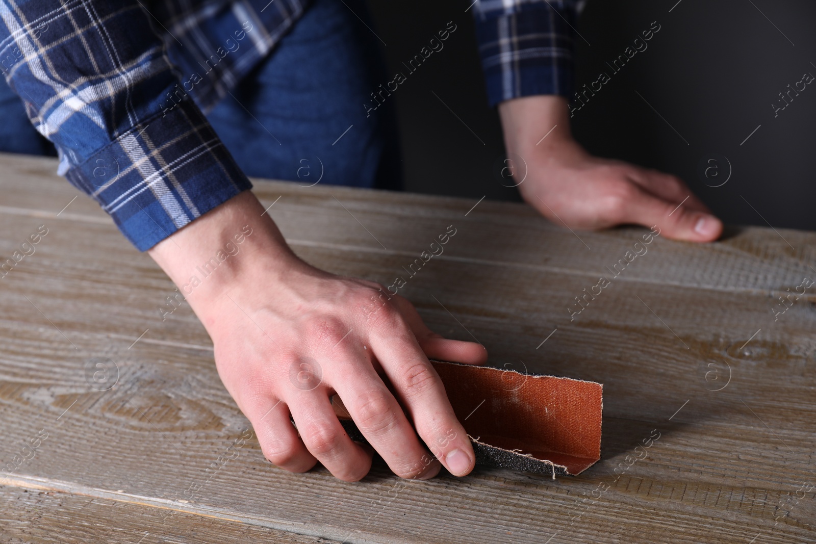 Photo of Man polishing wooden table with sandpaper, closeup