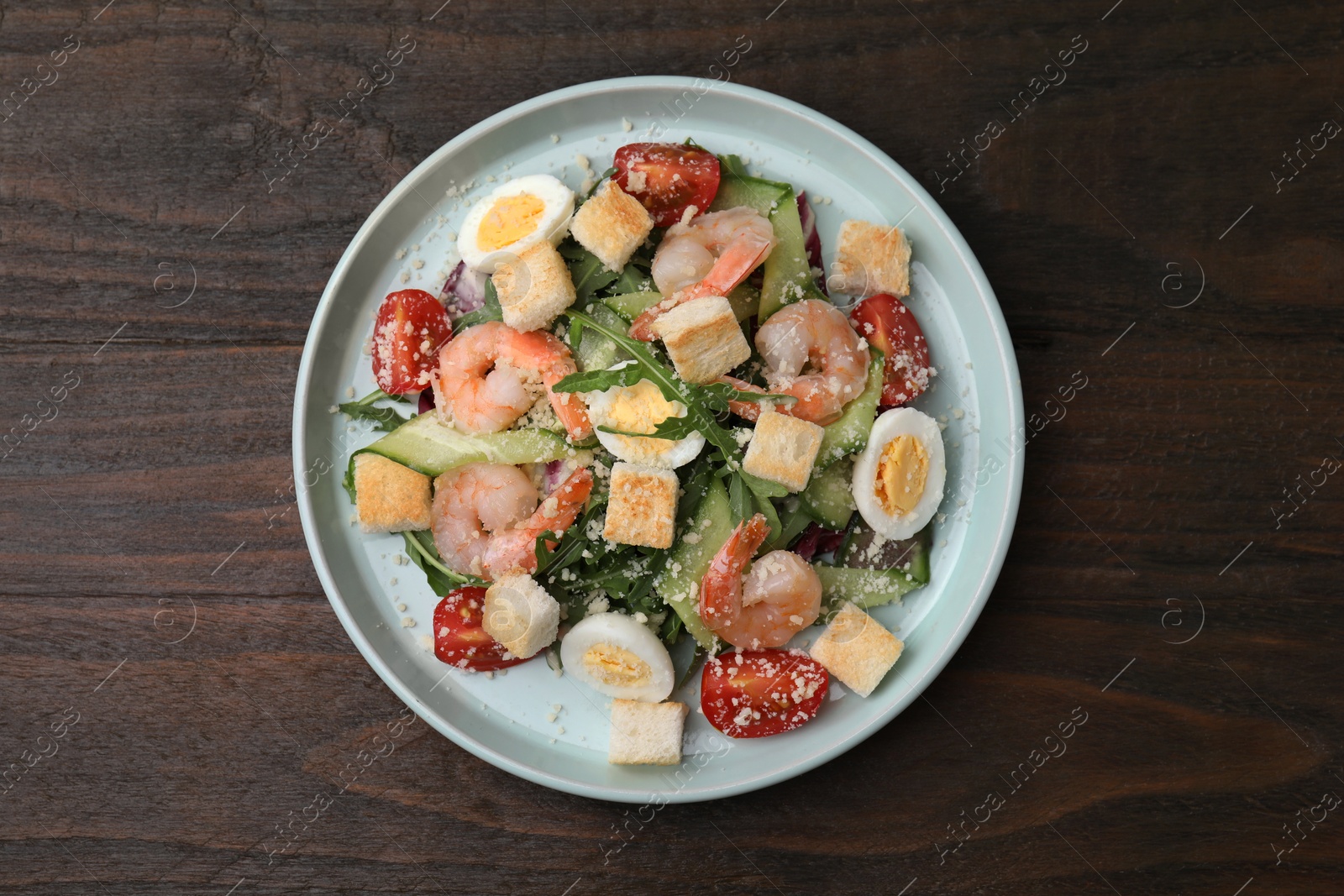 Photo of Delicious Caesar salad with shrimps on wooden table, top view