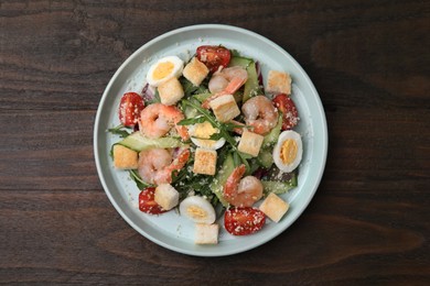 Photo of Delicious Caesar salad with shrimps on wooden table, top view