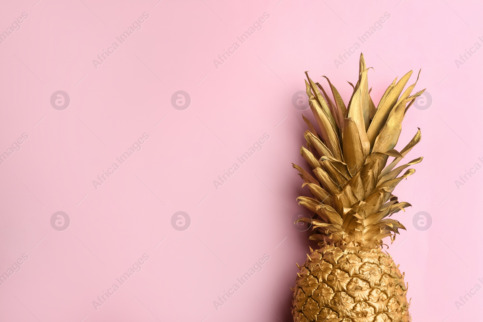 Photo of Top view of painted golden pineapple on pink background, space for text. Creative concept