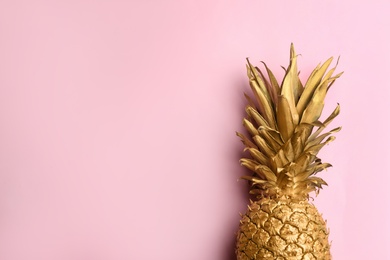 Photo of Top view of painted golden pineapple on pink background, space for text. Creative concept