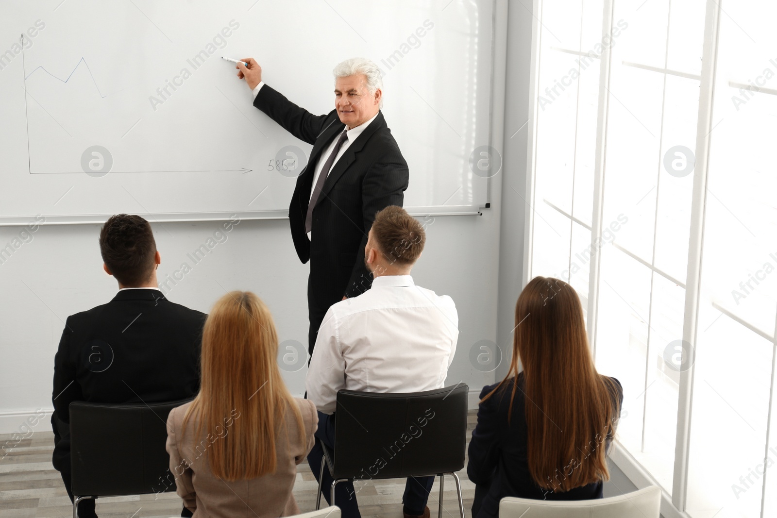 Photo of Senior business trainer working with people in office