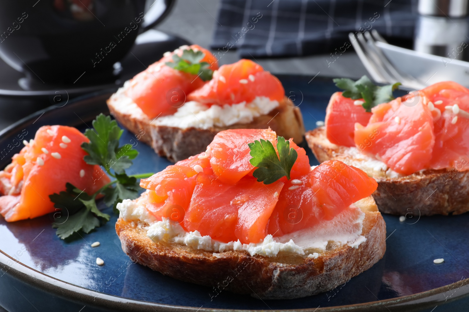 Photo of Tasty bruschettas with salmon, cream cheese and parsley on plate, closeup