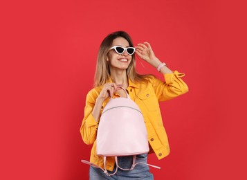 Photo of Happy woman with backpack on red background