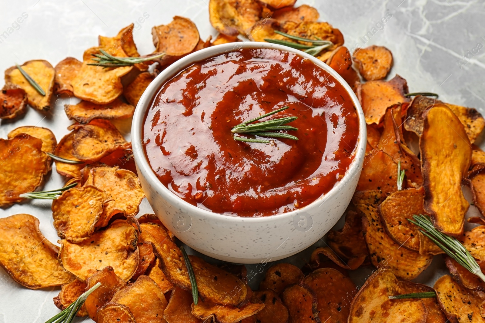 Photo of Sweet potato chips and bowl of sauce on grey background