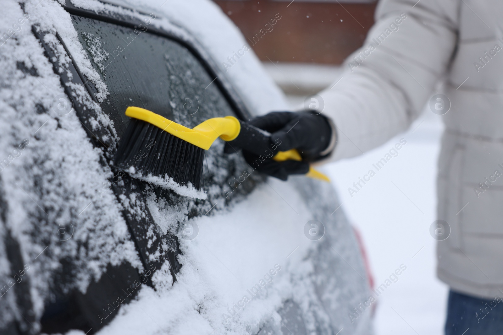 Photo of Man cleaning snow from car outdoors, closeup